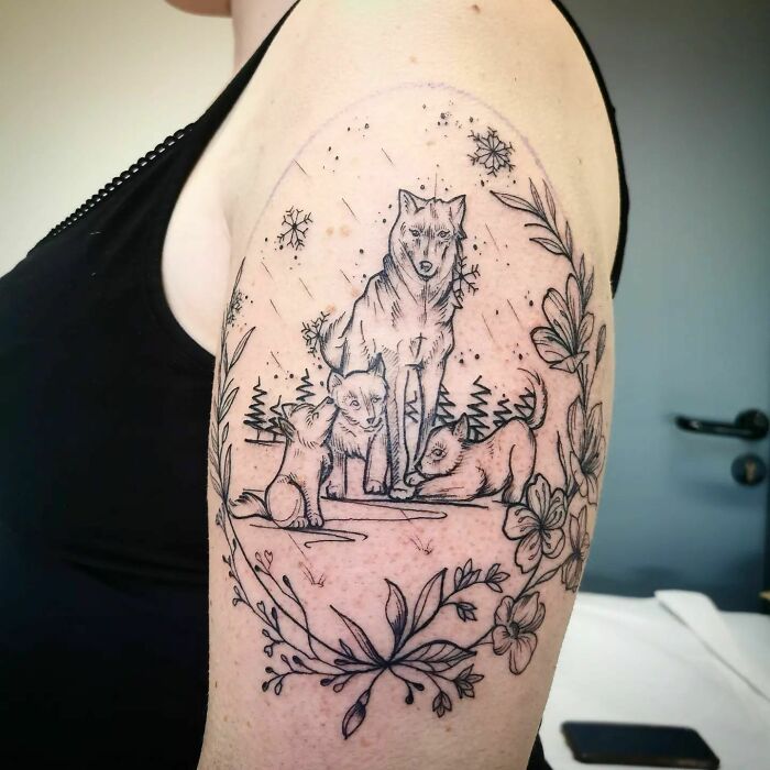 Wolf family tattoo on arm symbolizes beautiful mom and child bond, surrounded by floral designs.