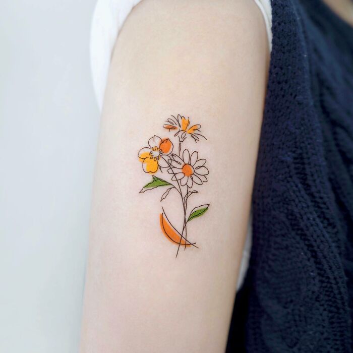 A delicate floral mom tattoo on an arm, symbolizing the mother-child bond with orange and white flowers.