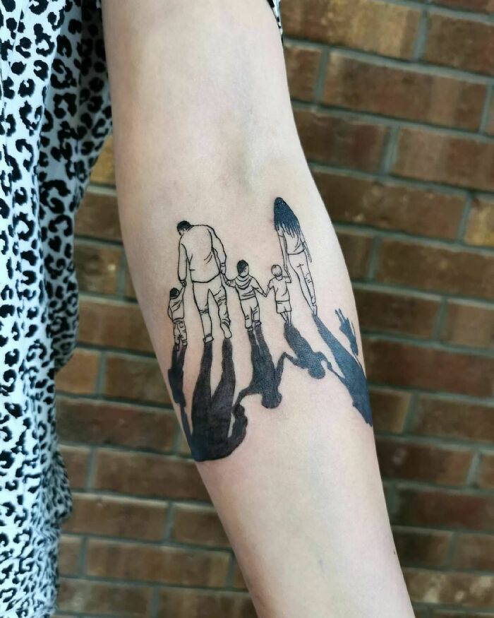 Forearm tattoo illustrating a mother and children walking, symbolizing the mother-child bond.