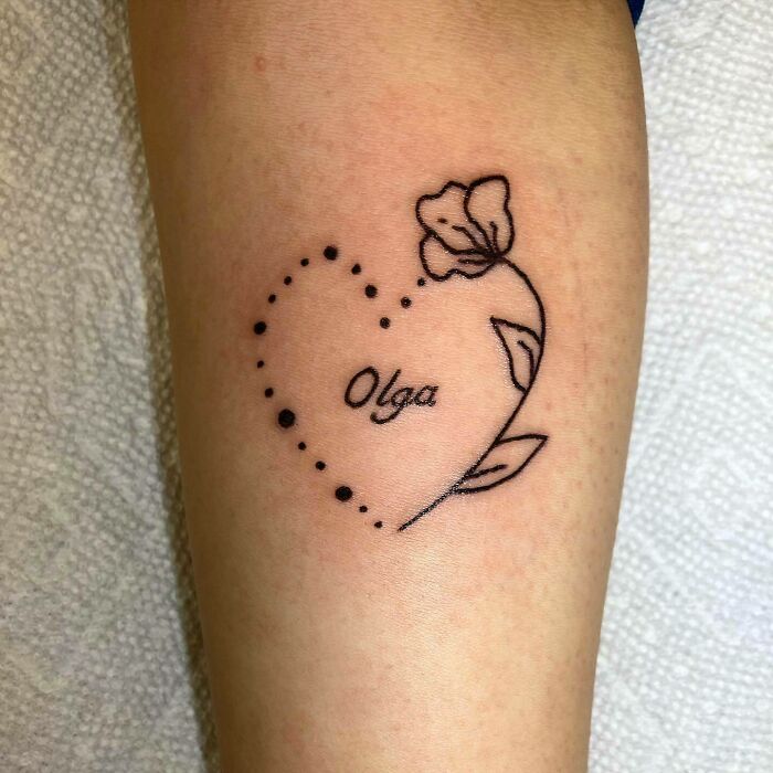 Heart-shaped mom tattoo with flower design, featuring name "Olga" inside, symbolizing mother-child bond.