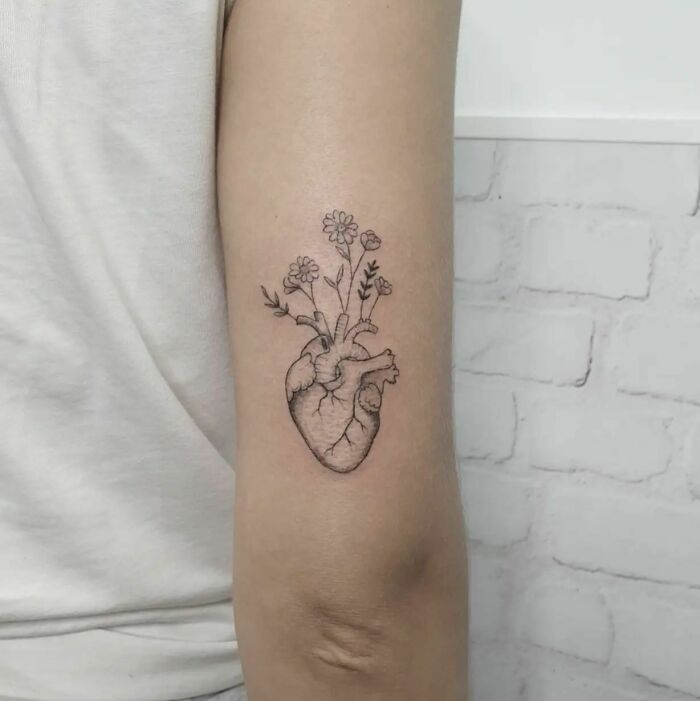 Heart tattoo with flowers on arm, symbolizing the mother-child bond.