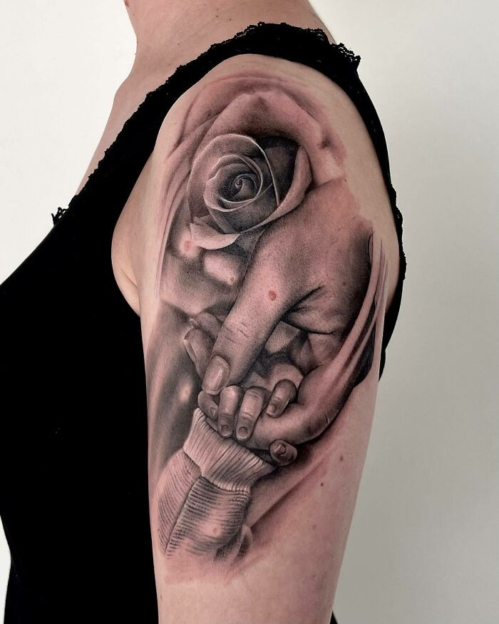 Arm tattoo of a mother and child holding hands with a rose, symbolizing the mother-child bond.