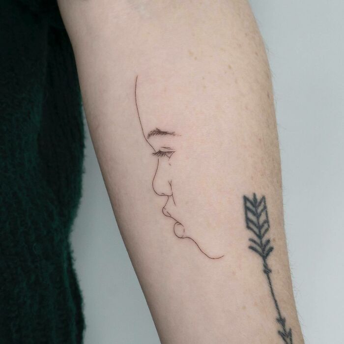 Minimalist mom tattoo featuring a child's profile, beautifully celebrating the mother-child bond.