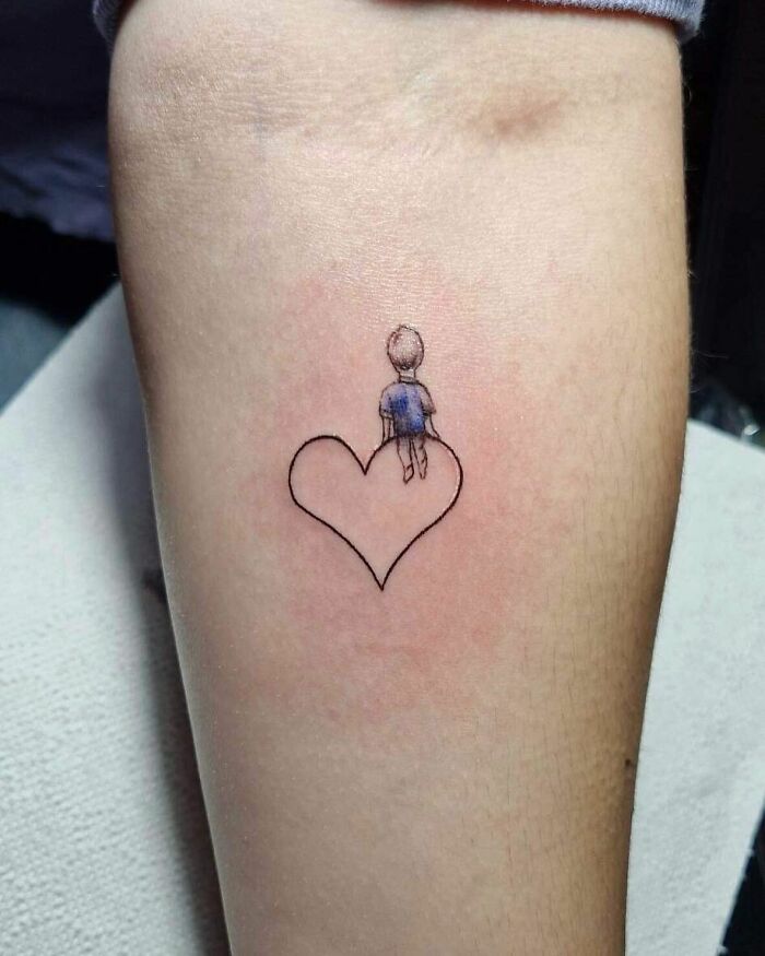 Heart tattoo featuring a child figure, symbolizing the mother-child bond.