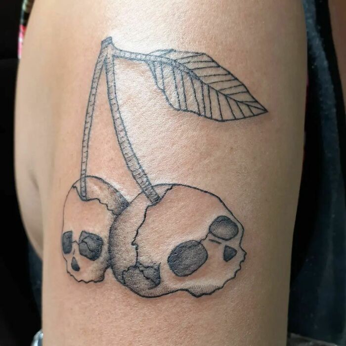 Skull cherries tattoo on arm, symbolizing unique mom-child bond.