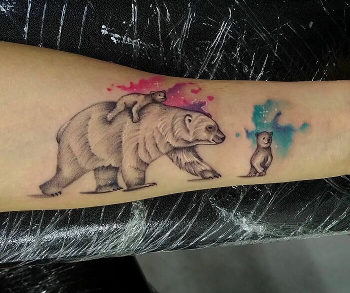 Bear family tattoo symbolizing the mother-child bond with colorful background on forearm.