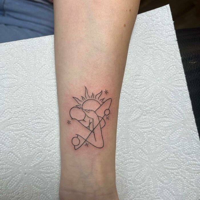 Minimalist mom tattoo featuring abstract sun, mother, and child design on forearm, celebrating mother-child bond.