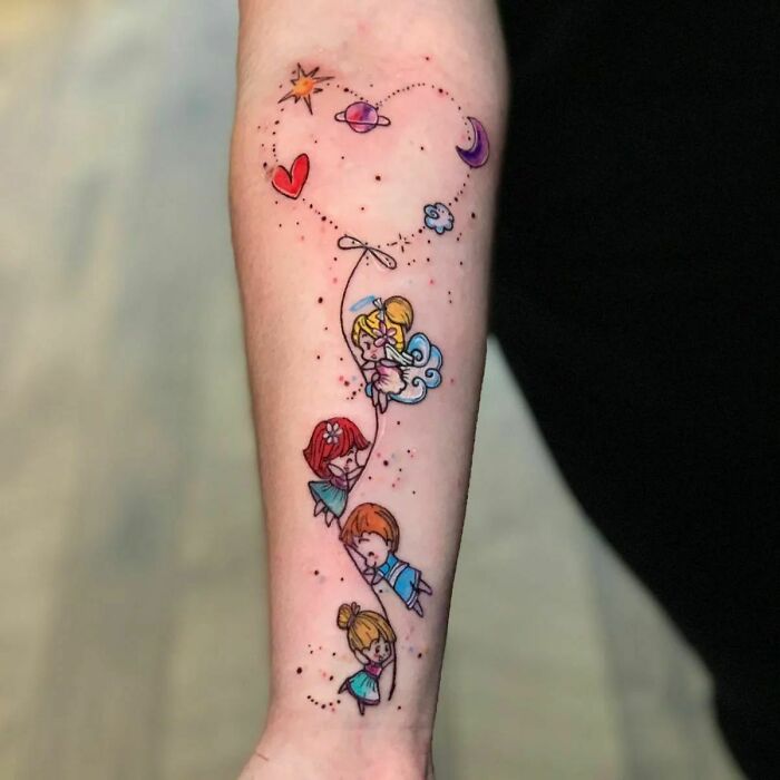 Colorful mother-child bond tattoo with children and celestial elements on a person's forearm.