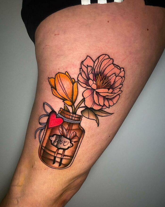 Colorful mom tattoo of flowers in a jar with a heart tag, symbolizing the mother-child bond.