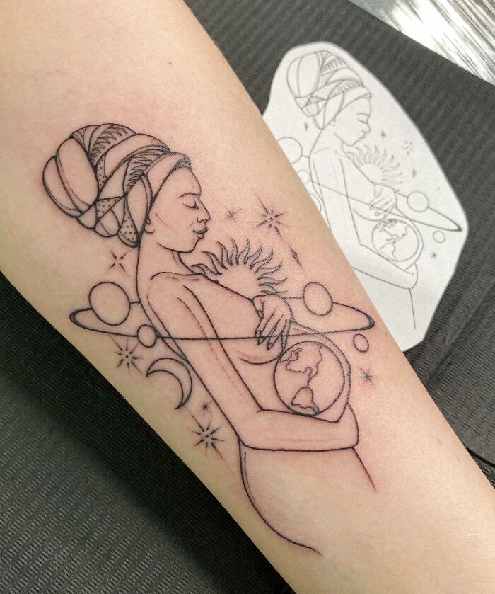 Mother-child bond tattoo with Earth, sun, and planets on arm, symbolizing a universal connection.