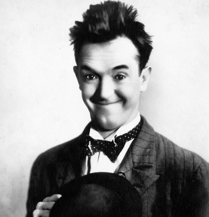 Stan Laurel smiling, wearing a bow-tie and suit, representing famous people who got married multiple times.