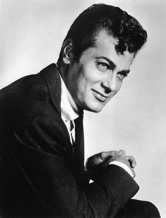 Tony Curtis wearing a dark jacket, one of the famous people who got married multiple times, posing in a classic black and white portrait.