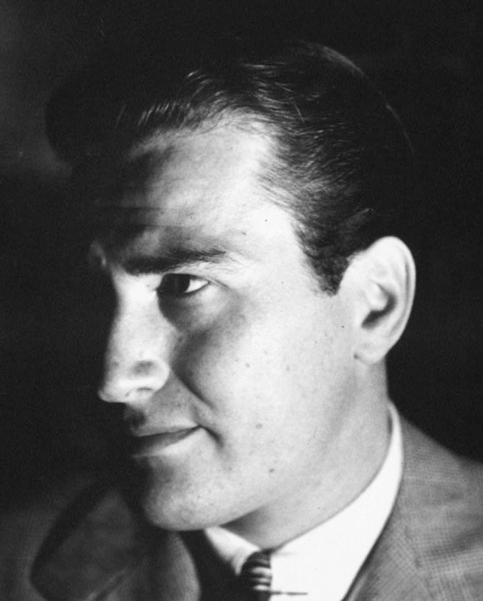 Artie Shaw in a suit and tie, a famous person known for getting married multiple times, in a classic black and white photo.
