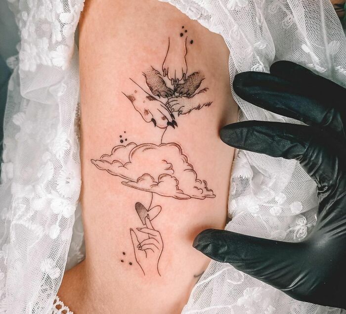 Pet tattoo design featuring a hand and paw reaching through a cloud on a person's arm.