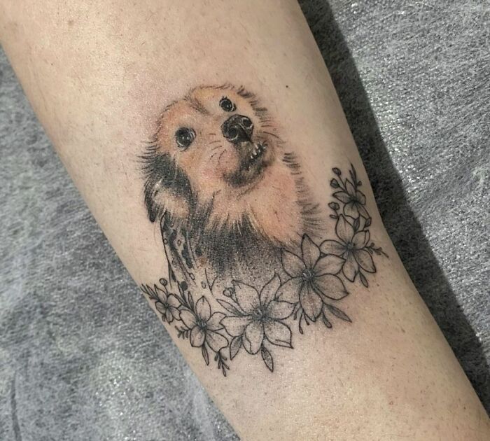 Dog-themed pet tattoo with floral accents, capturing the bond between humans and pets.