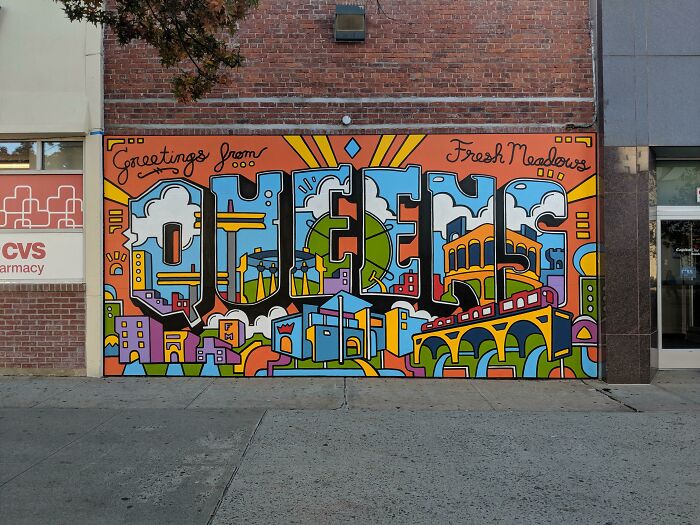 Colorful mural on a brick wall spelling Queens with vibrant cityscape, representing New York's unique urban art and culture.