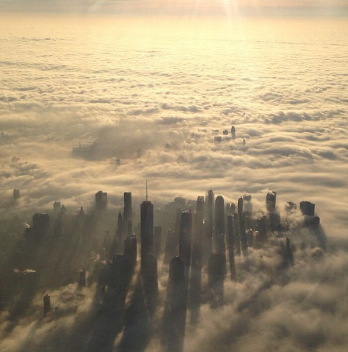 Aerial view of New York skyscrapers piercing through a thick layer of clouds showcasing the city's unique skyline.