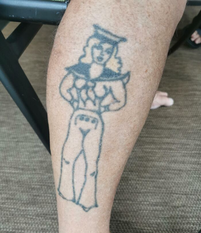 Aged tattoo of a sailor-style figure on a person's calf, showing ink changes over the years.