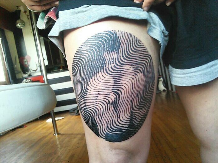 Optical illusion tattoo on thigh with eye and mind-bending design, featuring a swirling pattern.