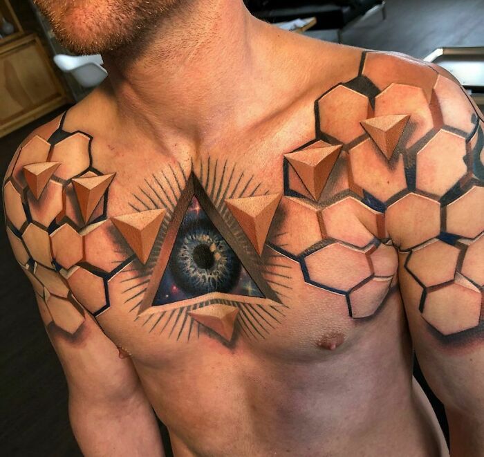 Chest optical illusion tattoo featuring a realistic eye within a geometric design.
