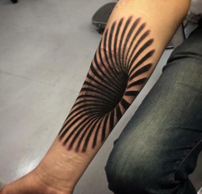 Optical illusion tattoo on forearm with spiral design, creating an eye and mind-bending effect.