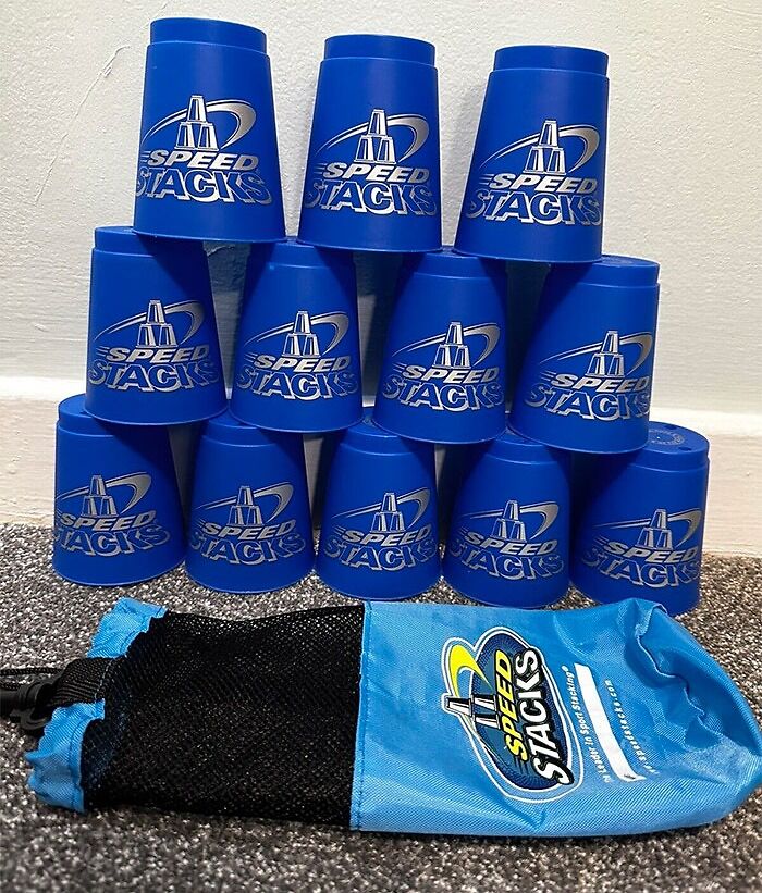 Blue speed stacks cups arranged in a pyramid with a matching blue carrying pouch on carpeted floor, highlighting big trends.