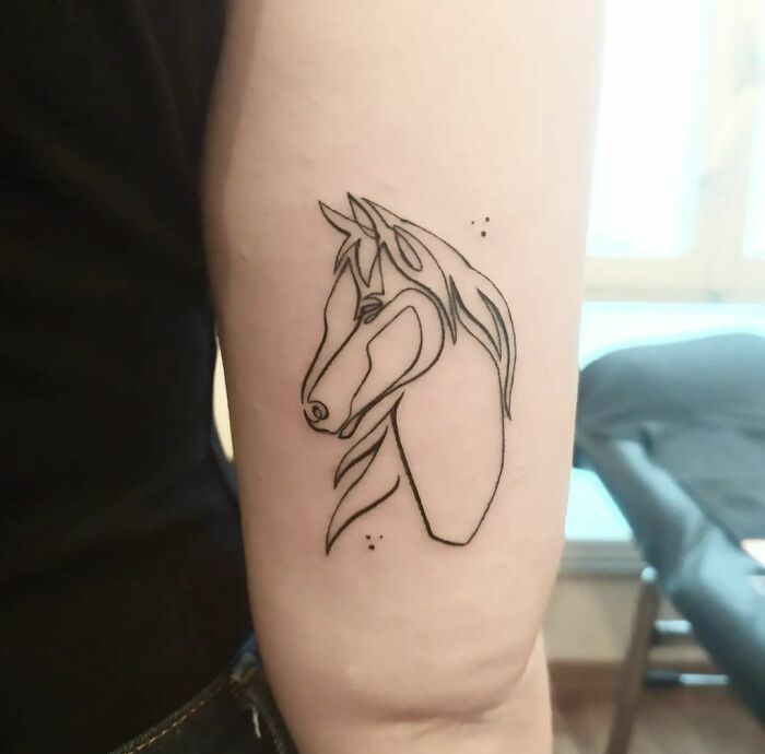 Minimalist line tattoo of a horse on an arm.