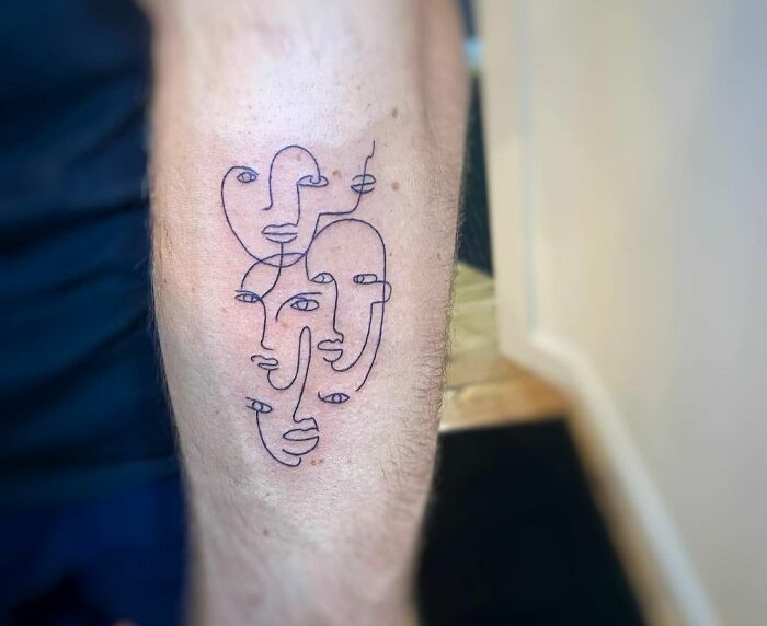 Minimalist line tattoo featuring abstract faces on a person's arm.