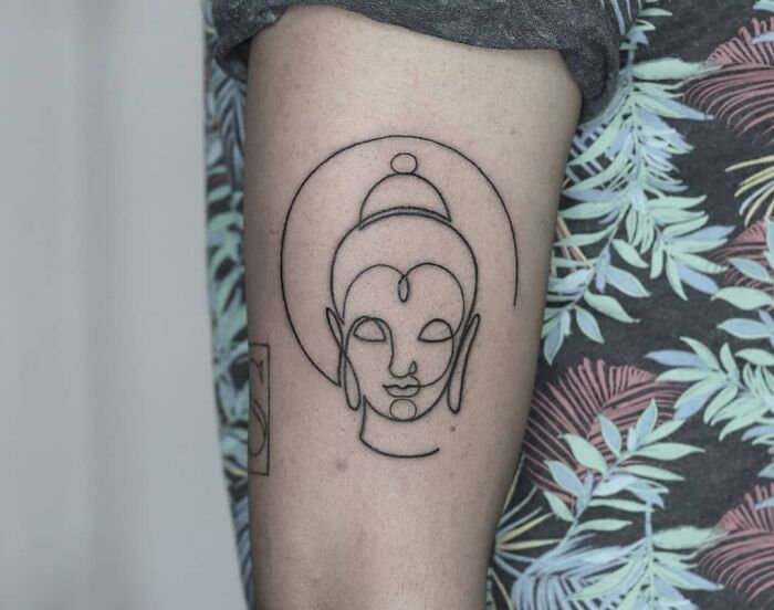 Minimalist line tattoo depicting a serene face on an arm, ideal for enthusiasts of unique line tattoo designs.