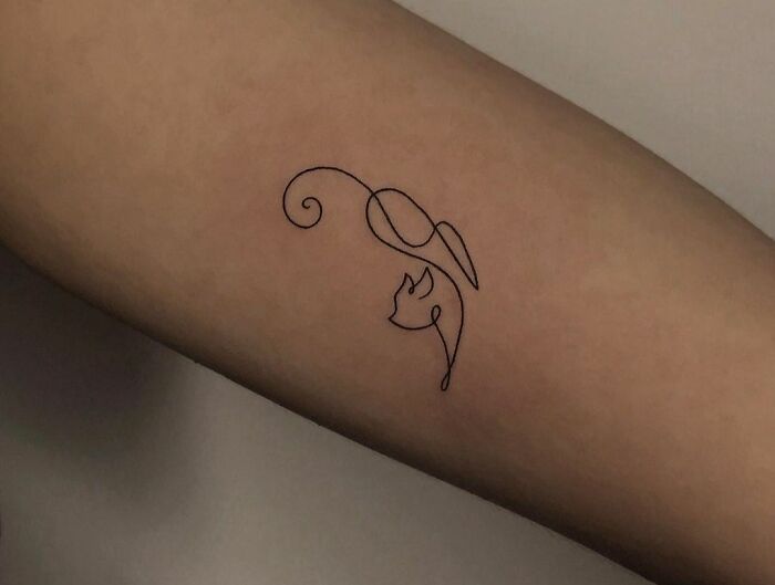 Minimalist line tattoo of a cat and flower on an arm.