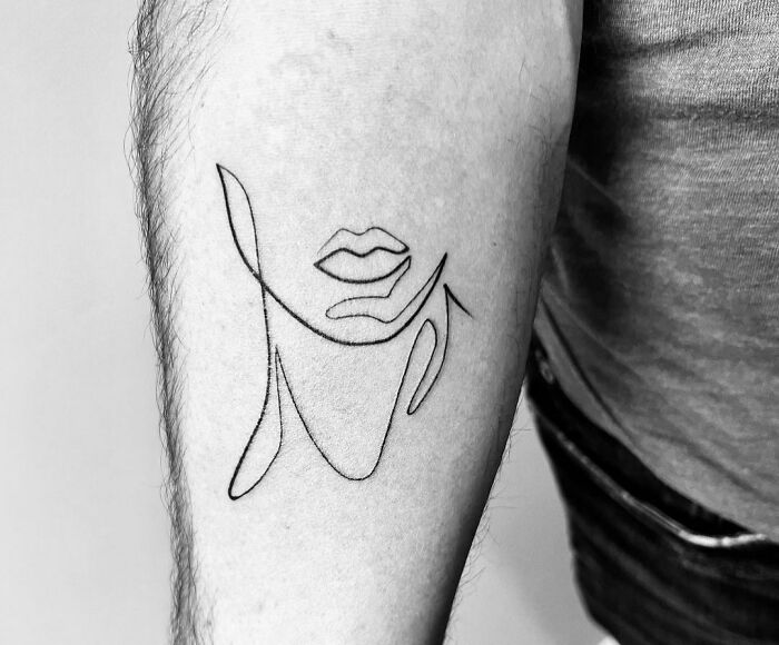Minimalist line tattoo of a face and lips on forearm, showcasing unique linear art.