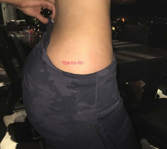 Celebrity tattoo on a person's side, reading “l'sa-ne-tè,” shown in a close-up photo indoors.