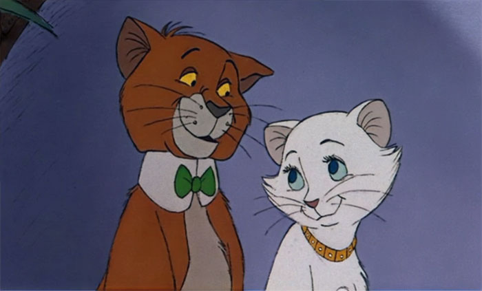 Cartoon couple of two cats, one brown with a green bow tie and the other white, looking at each other lovingly.