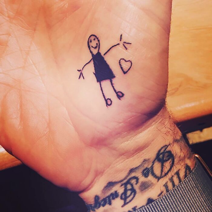 Stick figure tattoo on a David Beckham's palm with other tattoos visible on the wrist.