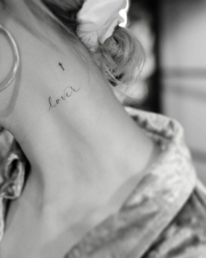 Neck tattoo of the word "lover" and a small cross, representing celebrity tattoos.