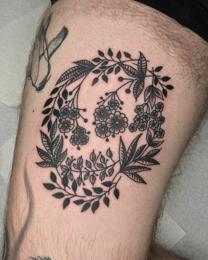 Optical illusion tattoo design of floral and leaf patterns on upper leg.