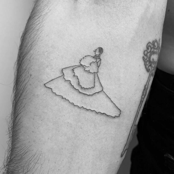 Celebrity tattoo of a woman in a gown, minimalist design on an arm.