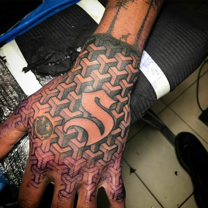 Optical illusion tattoo design on a hand featuring geometric patterns and intricate detailing.