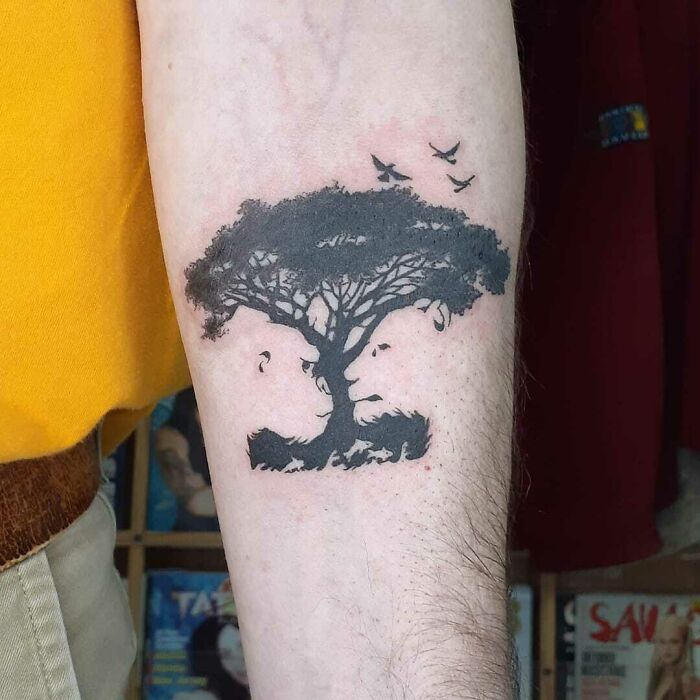 Optical illusion tattoo of a tree with birds on an arm, showcasing creative design.