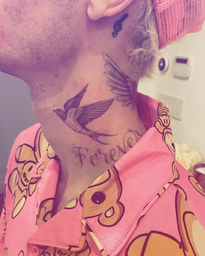Celebrity showcasing neck tattoo of a bird and the word "Forever" in a colorful shirt.