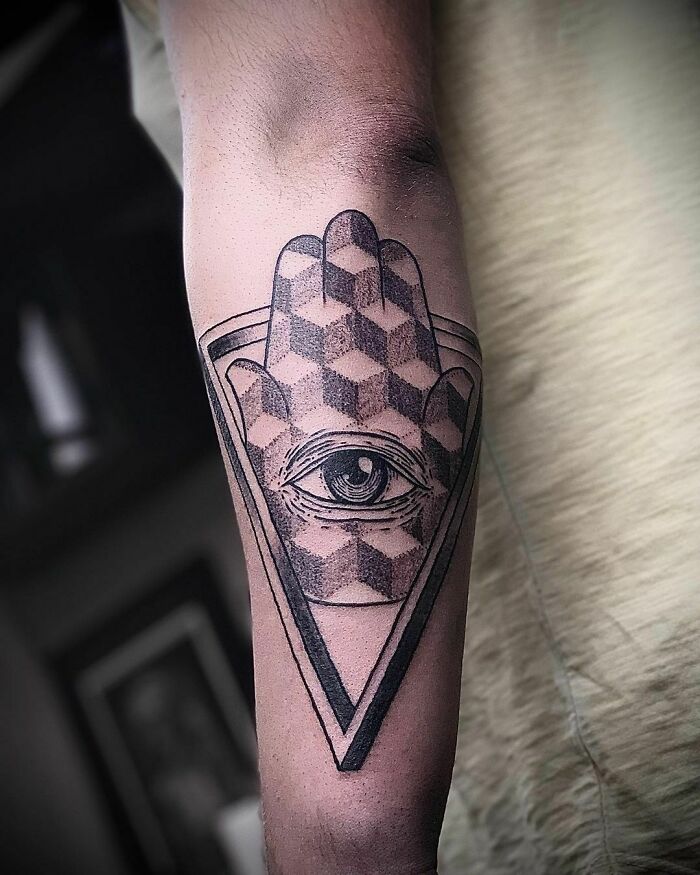 Optical illusion tattoo with eye design on arm, featuring geometric shapes for depth effect.