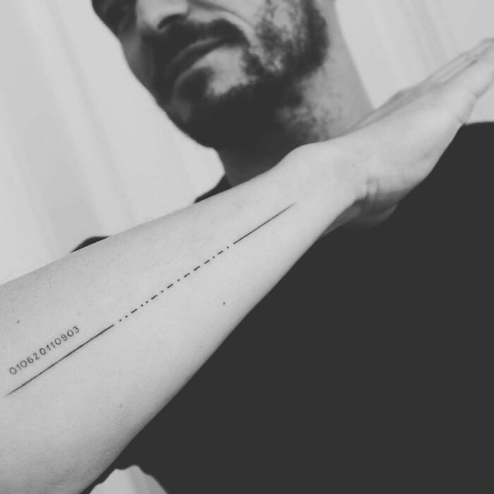Minimalist celebrity tattoo on forearm, featuring a long line and numbers.
