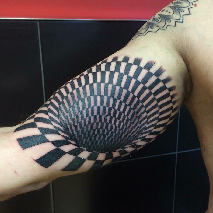 Optical illusion tattoo on arm, creating a 3D effect with a spiral design.
