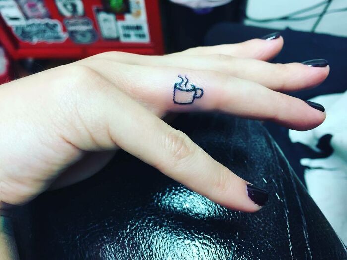 Finger with small coffee cup tattoo, inspired by celebrity tattoos.