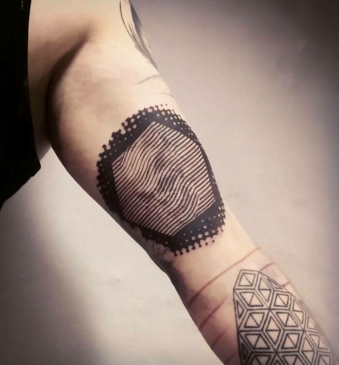 Arm with an optical illusion tattoo design featuring geometric shapes and lines.