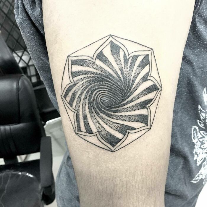 Optical illusion tattoo with spiral design on an arm, creating a mind-bending effect.