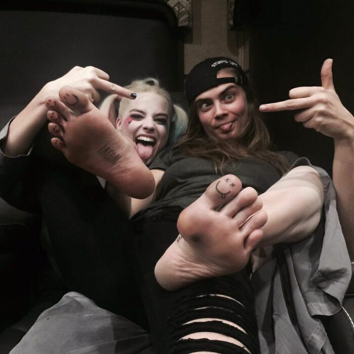 Two people showing foot tattoos and playful expressions, ideal for celebrity tattoo inspiration.