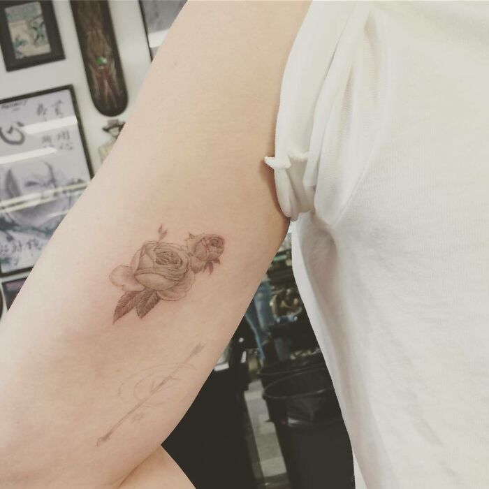 Rose tattoo on upper arm in a tattoo studio, showcasing celebrity tattoos inspiration.