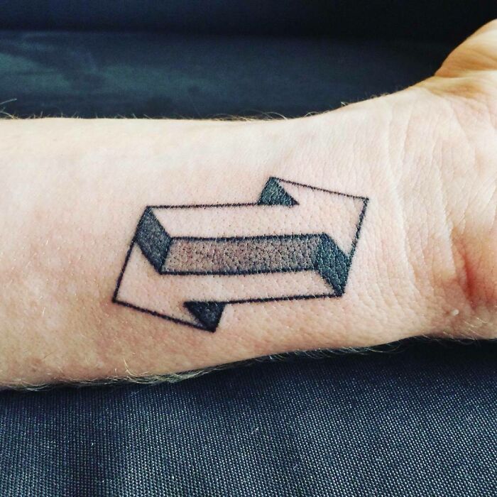 Optical illusion tattoo of a 3D arrow on a forearm, showcasing intricate design and shading.