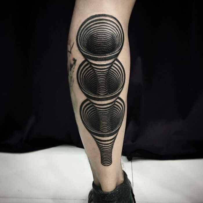 Optical illusion tattoo on calf with mind-bending design, featuring layered 3D circles creating a tunnel effect.